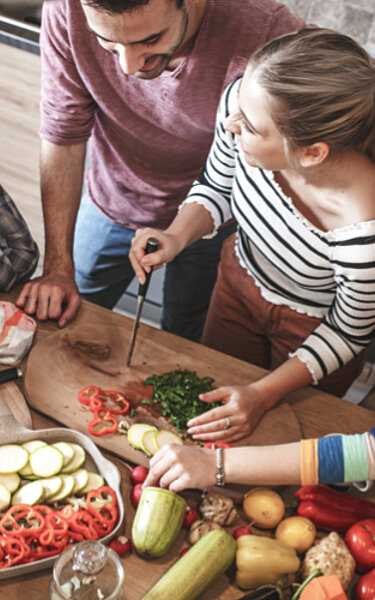 Vier Freunde bereiten gemeinsam gesundes Essen in der Küche zu.